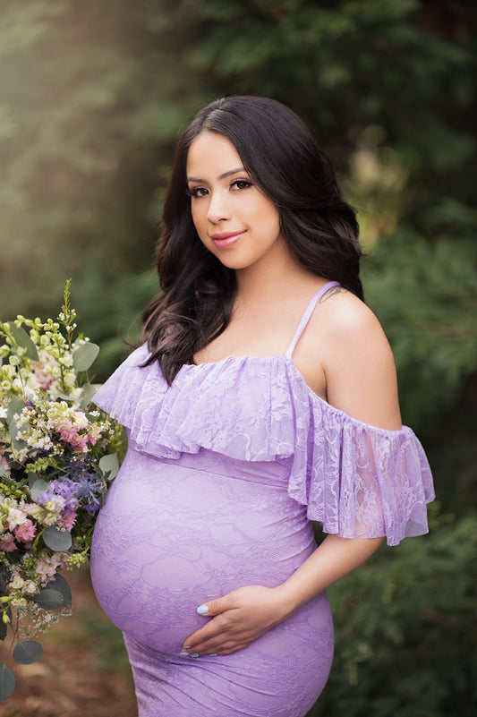 Woman wearing an allover lace maternity dress with a gathered bodice