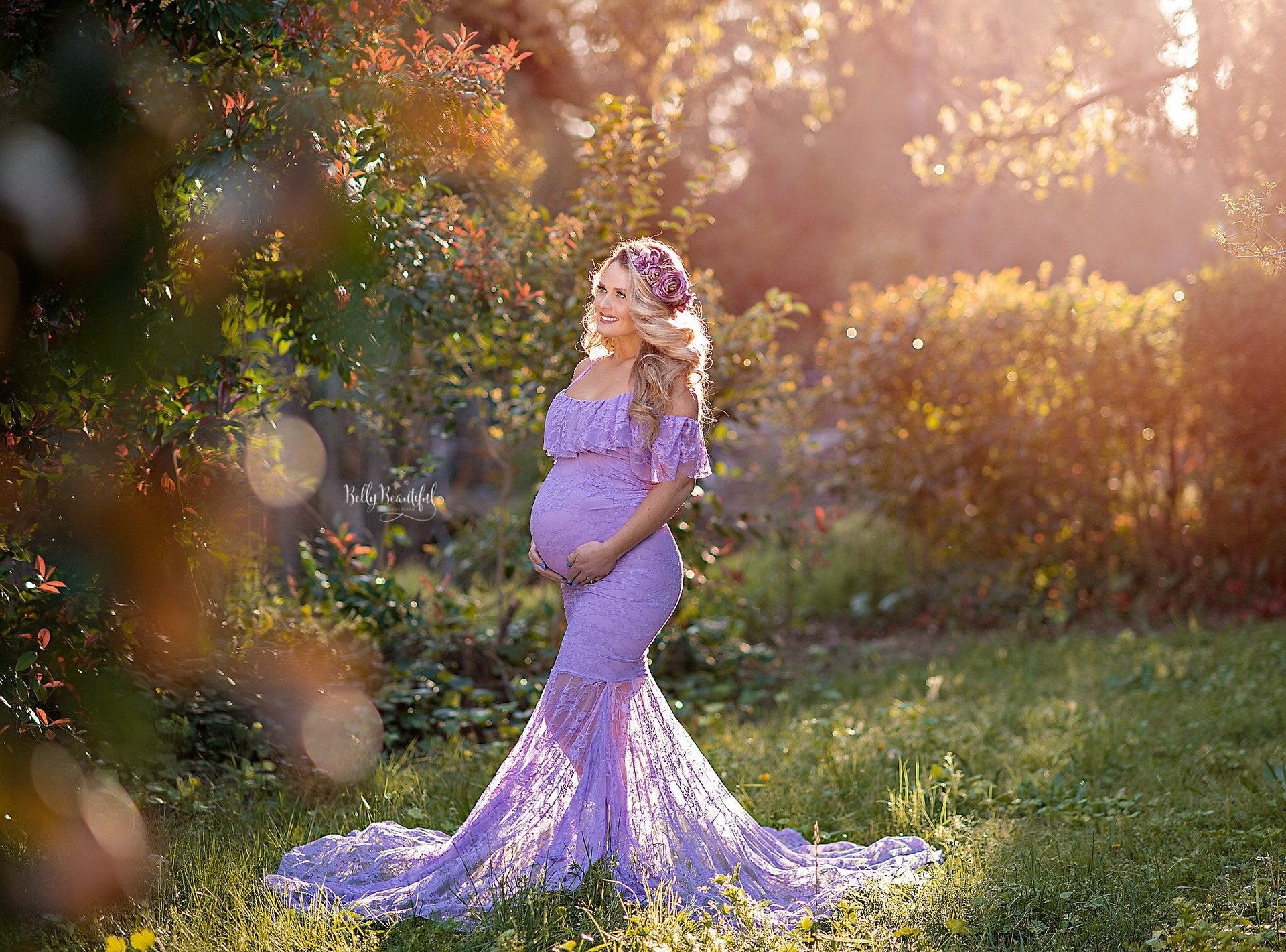 Woman wearing an allover lace lilac maternity dress with a gathered bodice