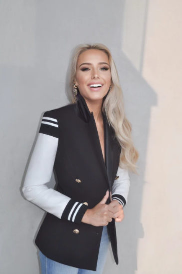 blonde woman wearing a varsity blazer jacket and smiling